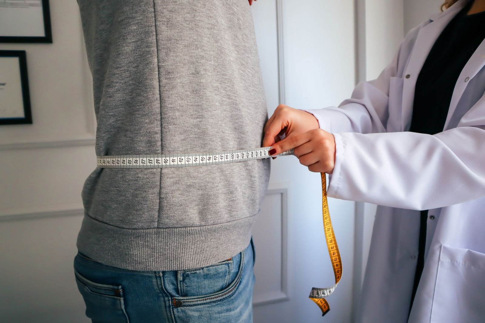 Nutritionist measuring a man's waist with a tape