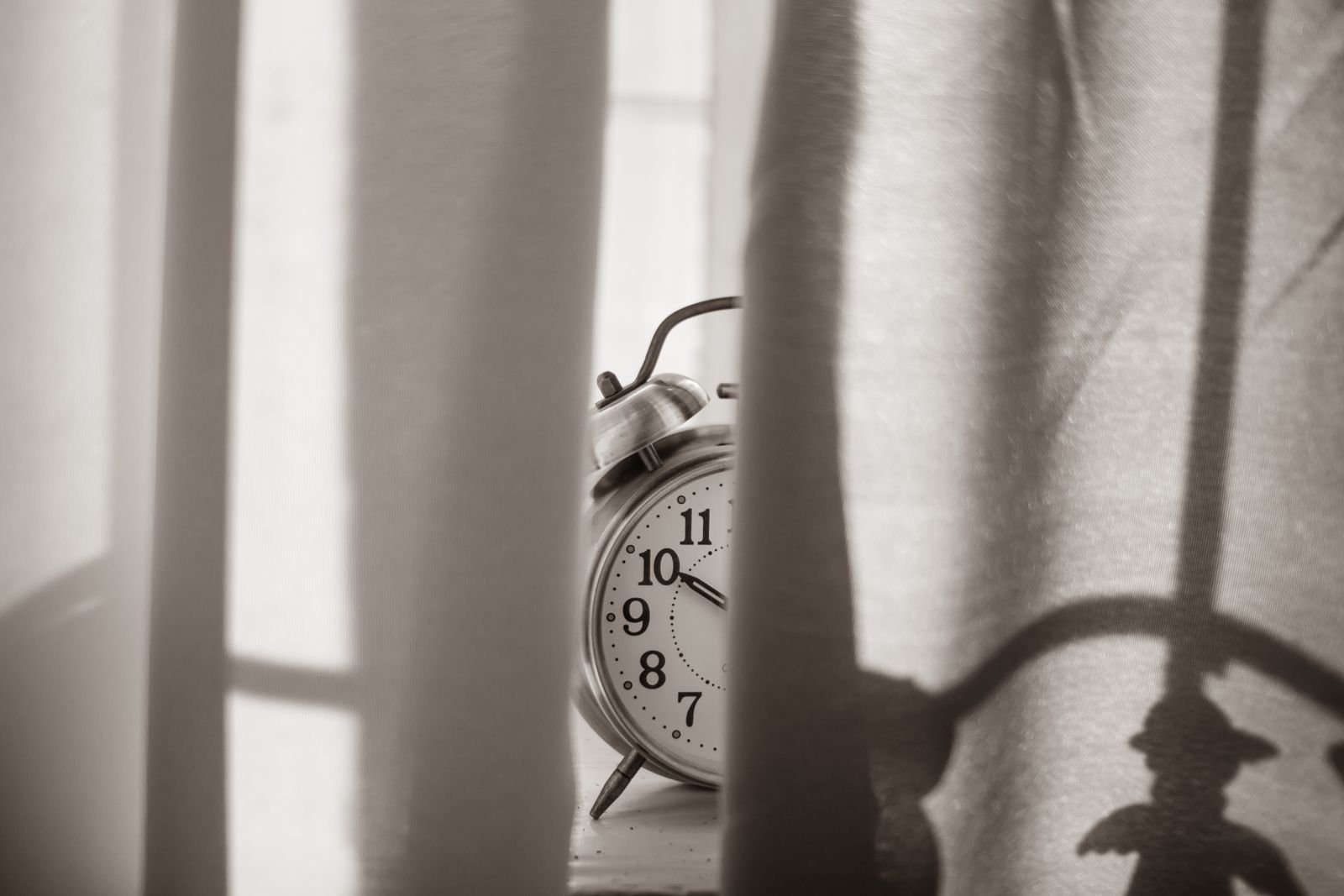 Old alarm clock beside a bedroom window