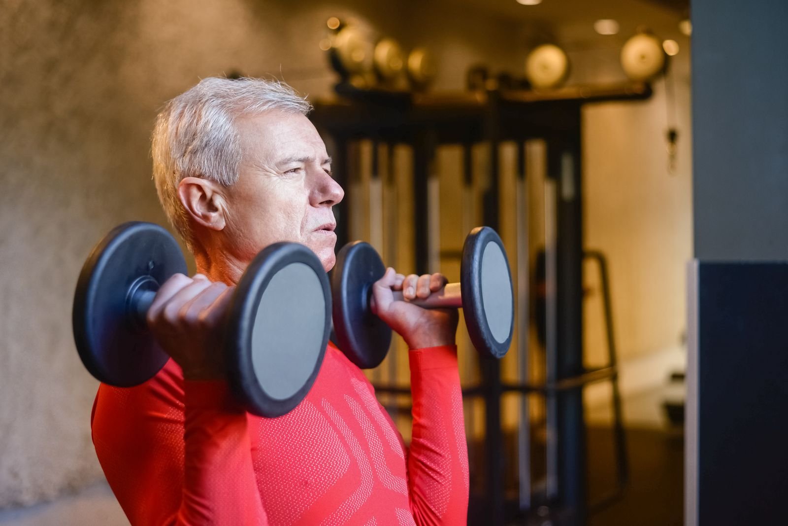 Older man lifting dumbbells in a gym