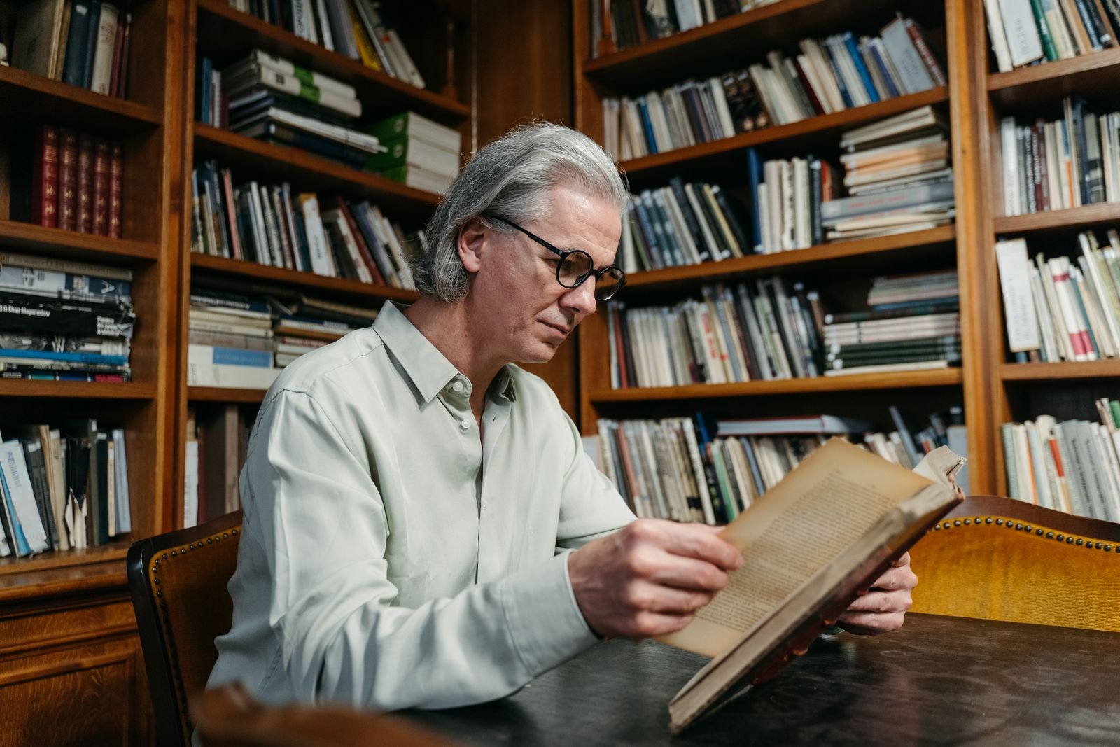 Older man reading a book in a library