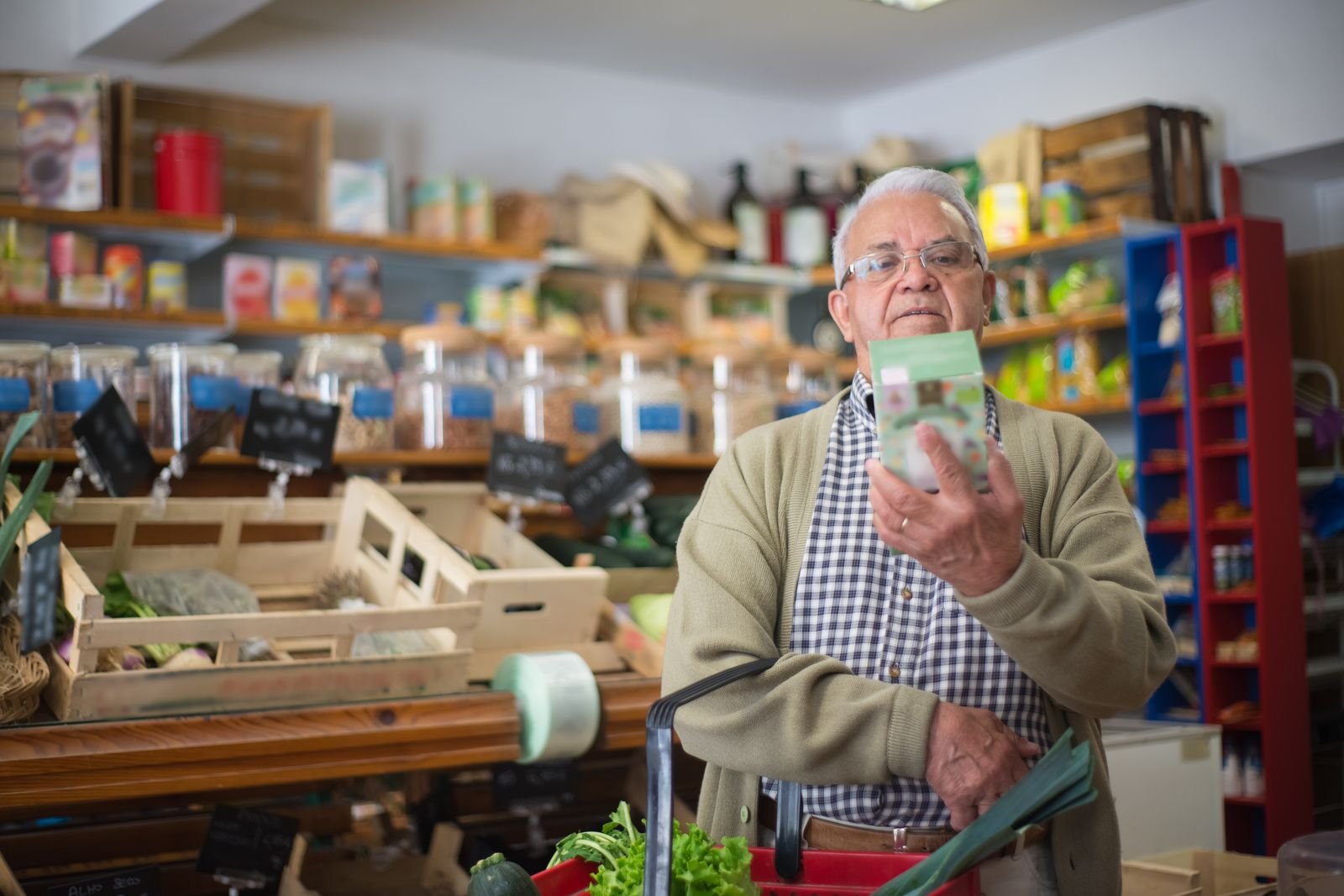 Older man reading a product label in a grocery aisle
