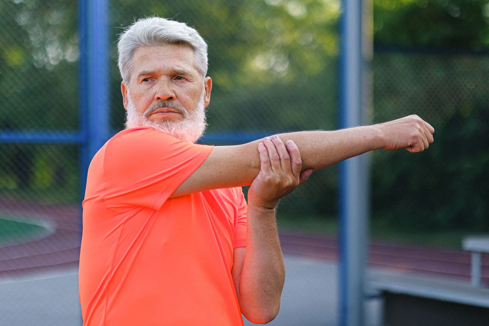Older man stretching before a workout at a stadium