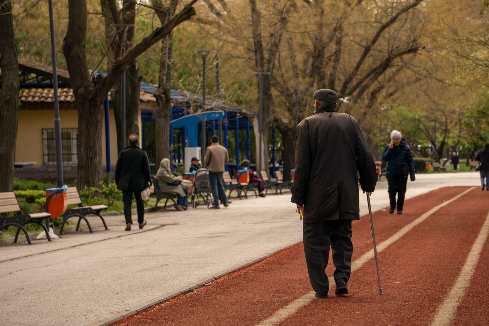 Older man walking with a cane on a park path
