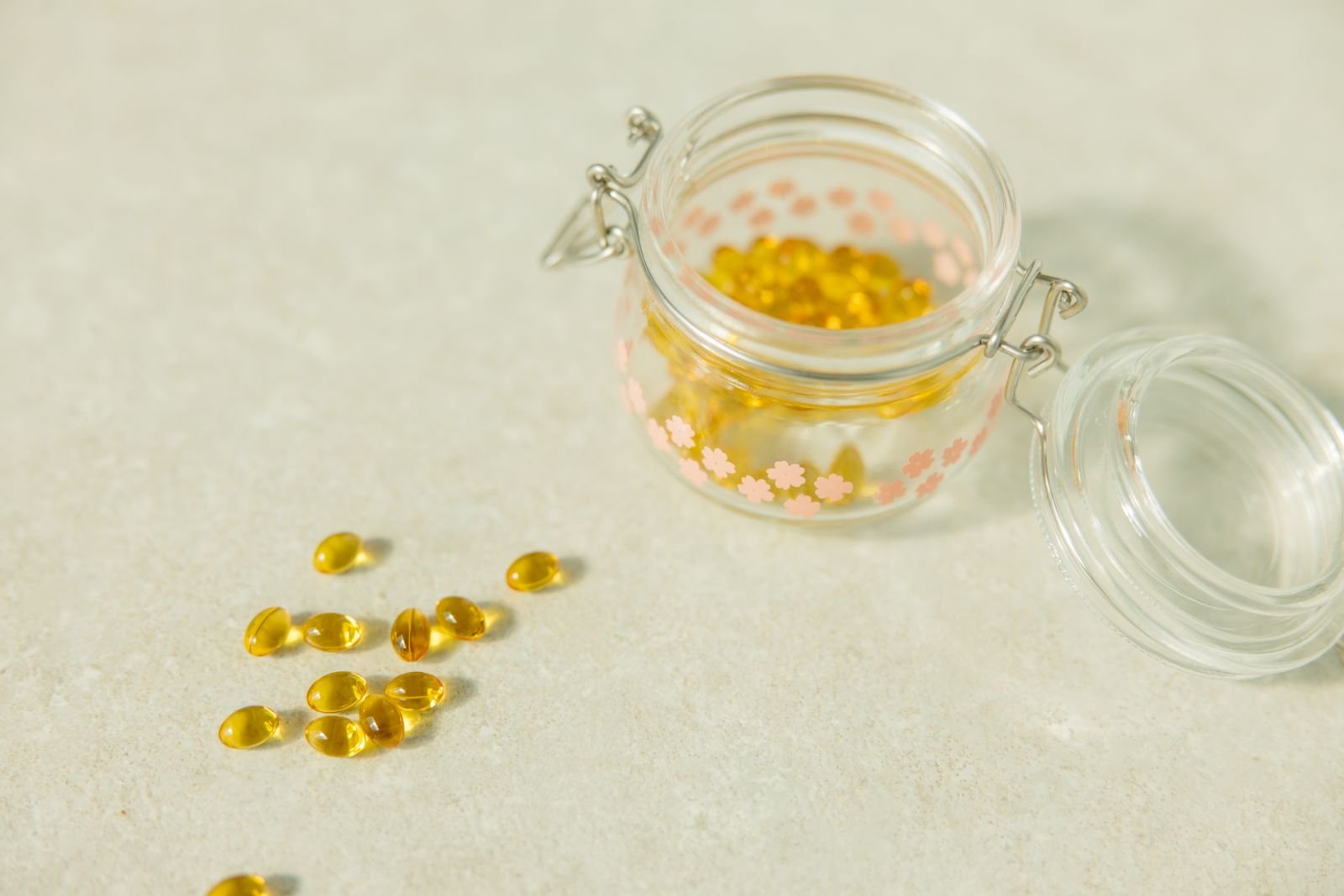 Open glass jar of yellow softgel capsules