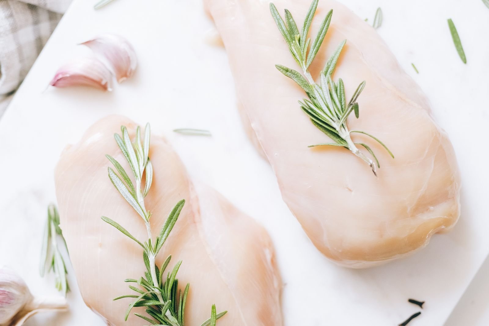 Raw chicken breasts with fresh rosemary