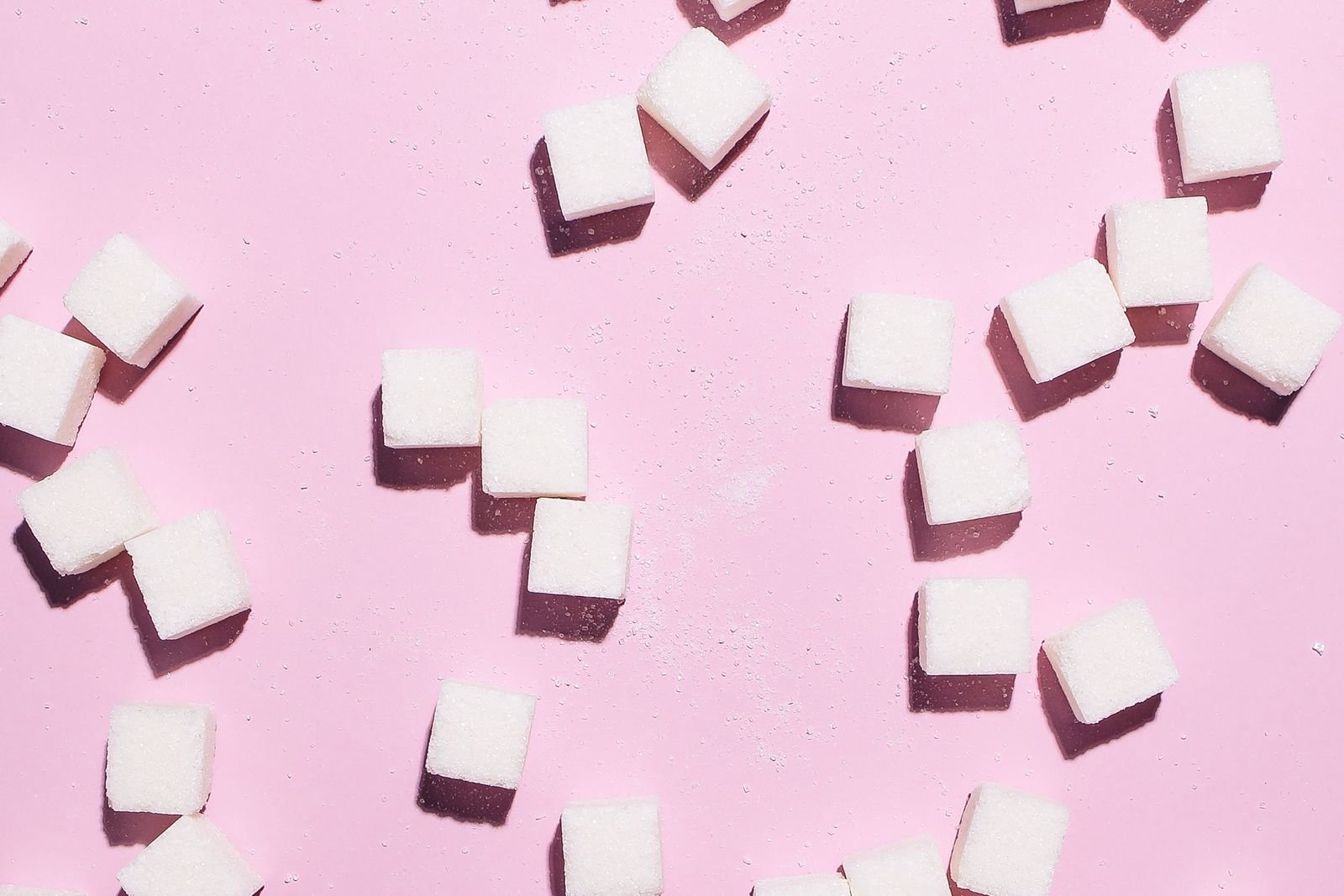 Sugar cubes scattered on a pink background