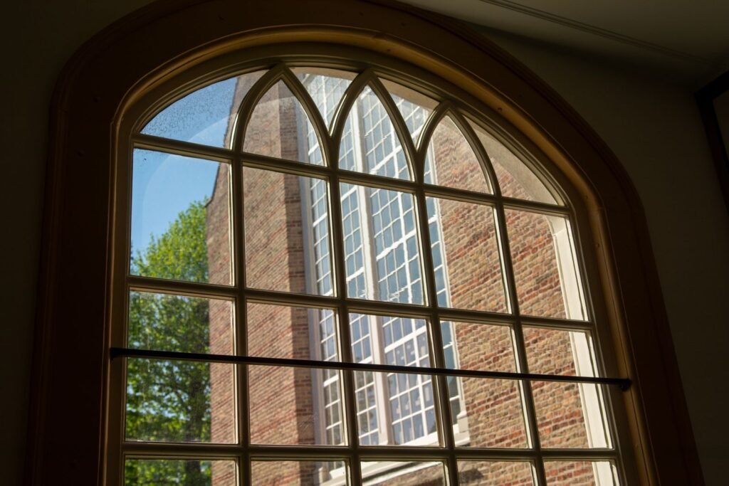 Sunlit brick building seen through an arched window