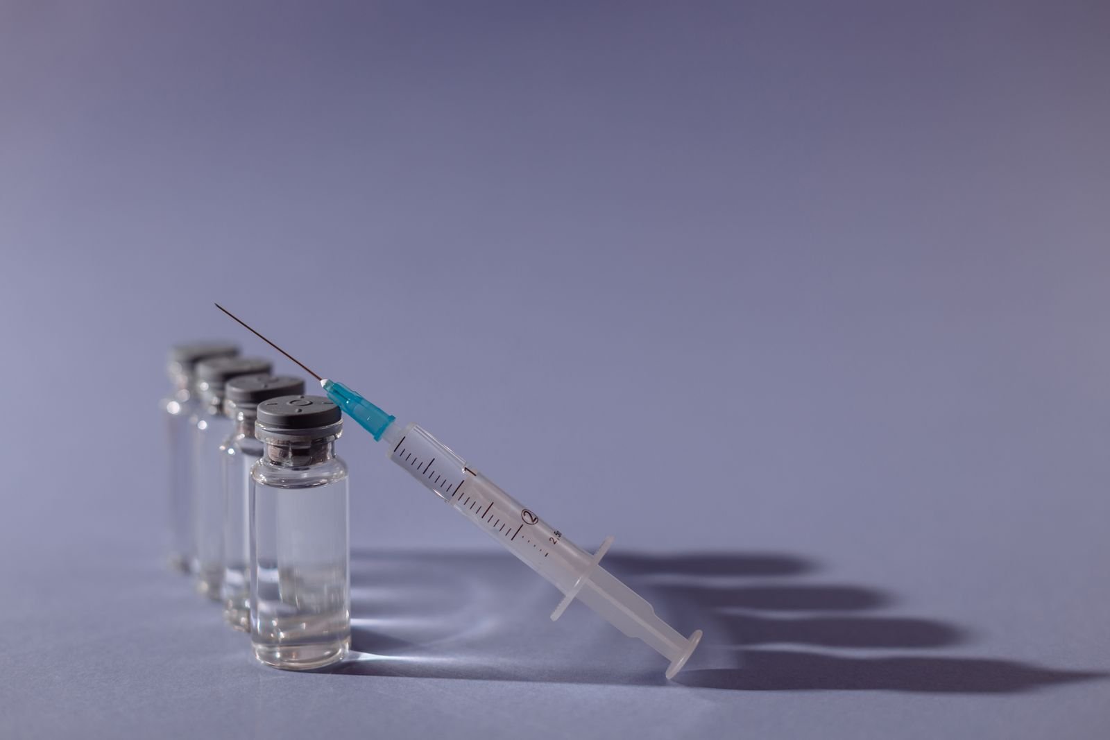 Syringe and glass vials on a grey surface