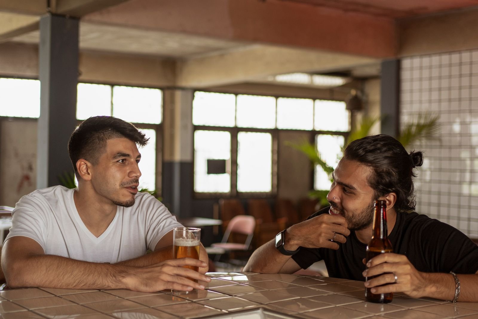 Two men talking over drinks at a bar