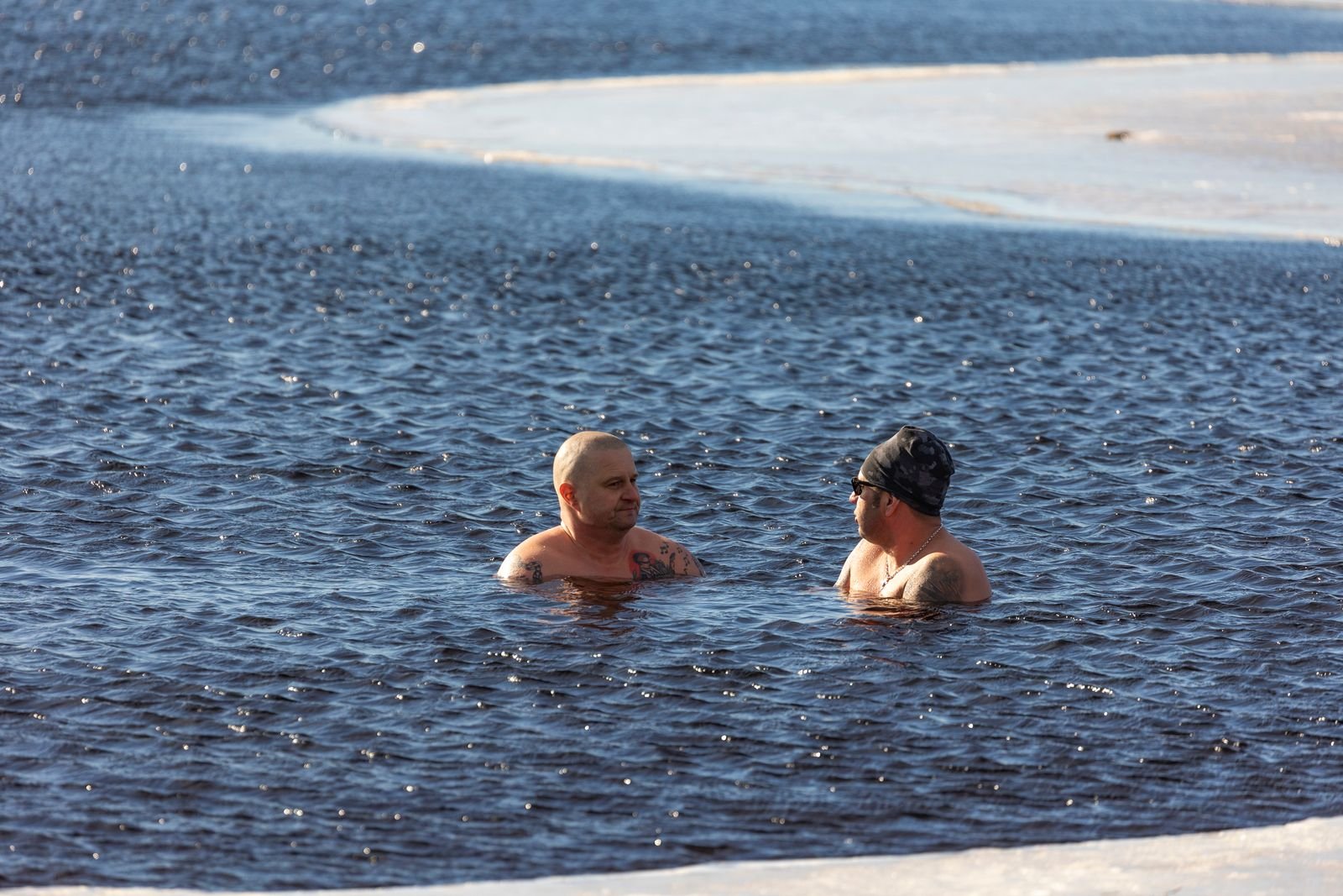 Two men winter swimming in icy water