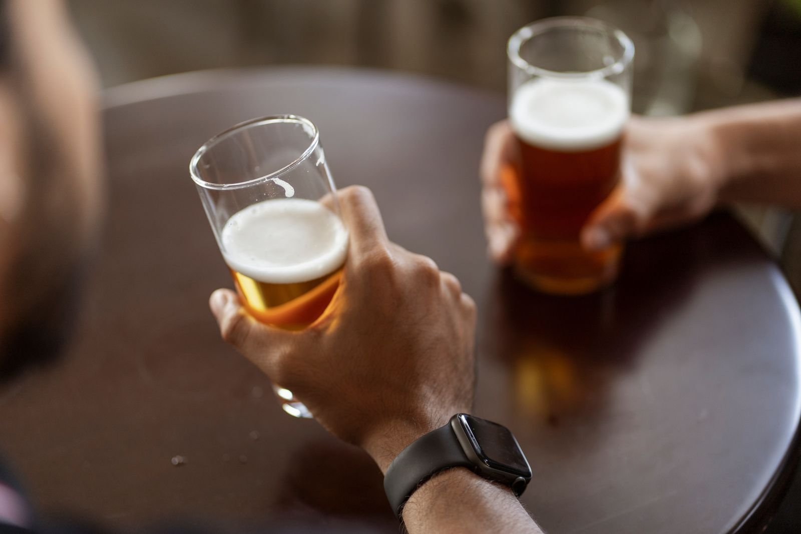 Two people holding glasses of beer