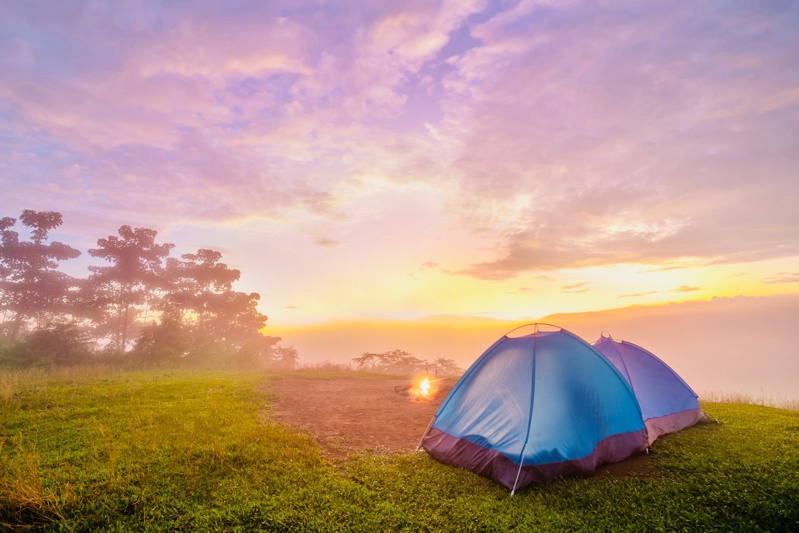 Two tents on a grassy hill at sunrise