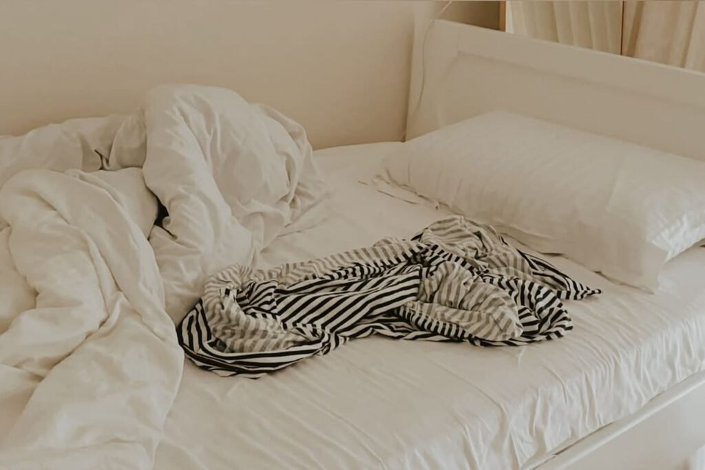 Unmade bed with crumpled white linens