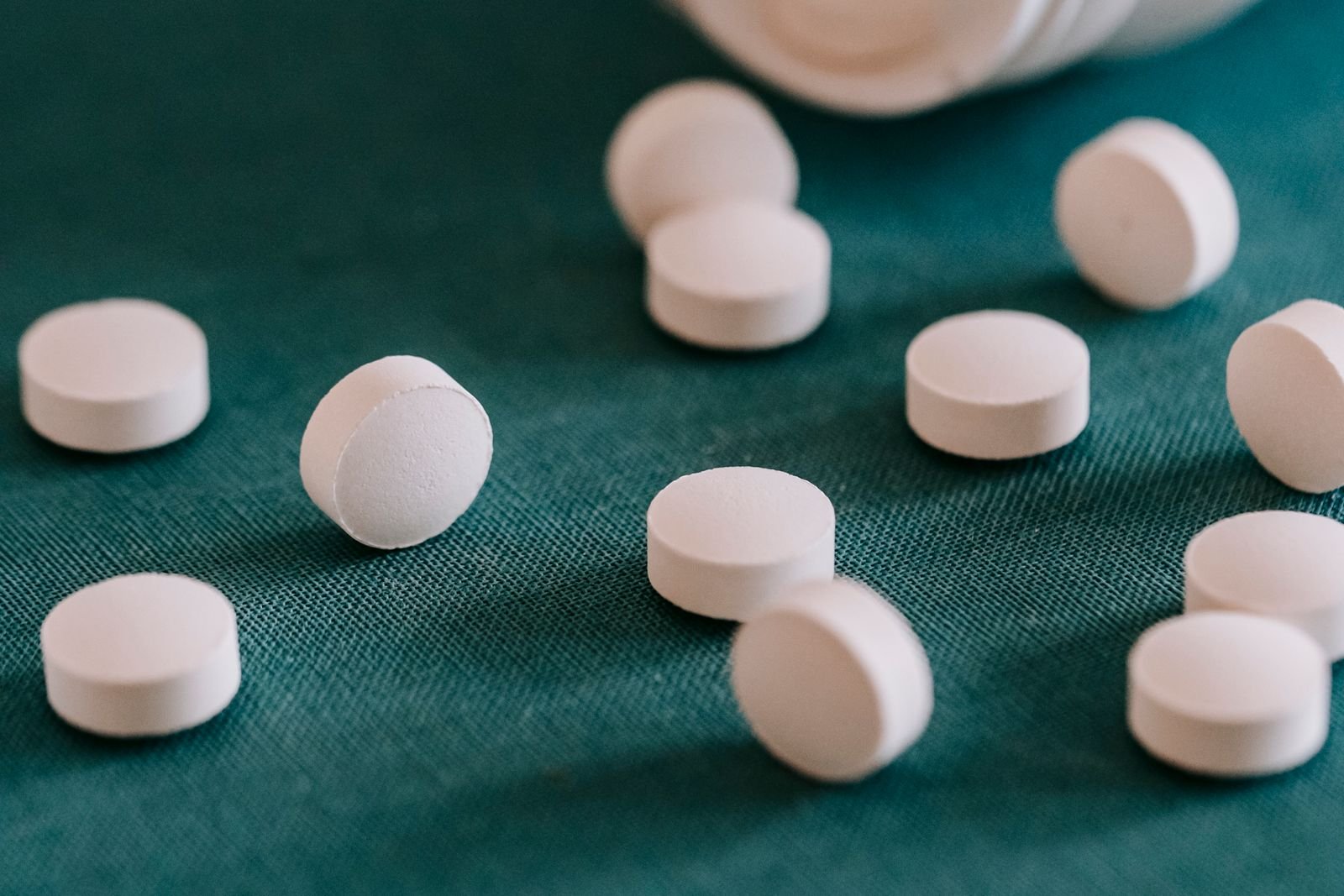 White tablets scattered on a dark surface