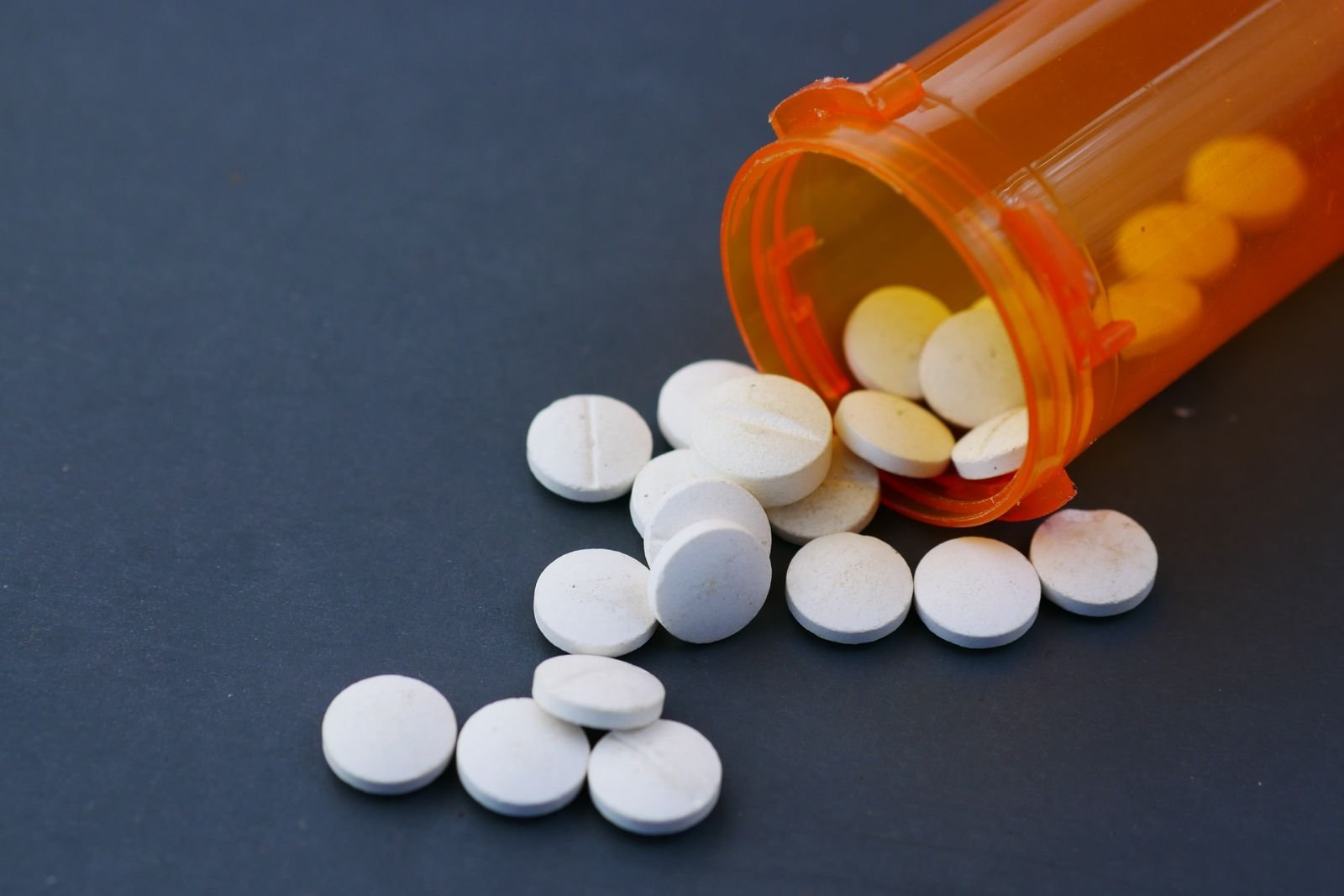White tablets spilling from an orange prescription bottle