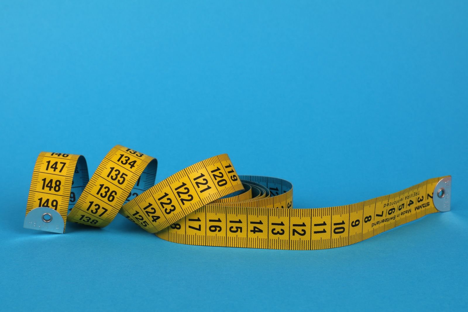 Yellow tape measures coiled on a blue background