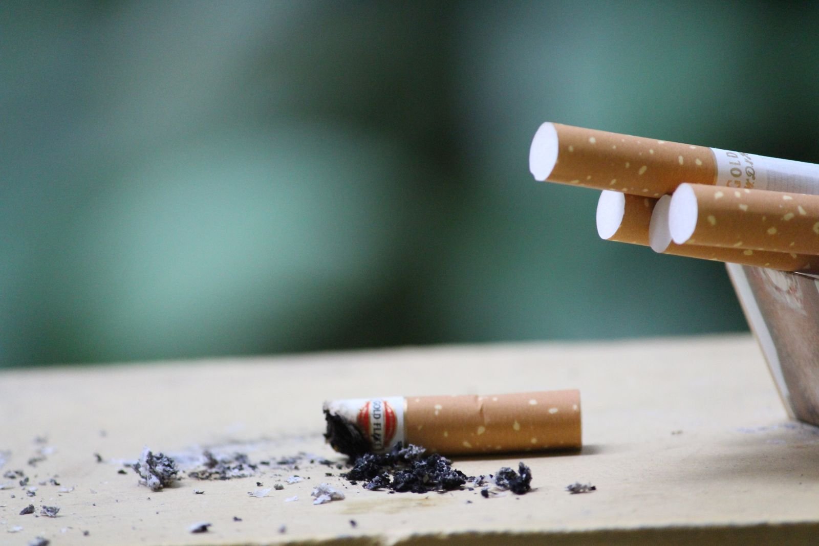 Cigarettes and ash on a table, a reminder of how smoking harms the heart