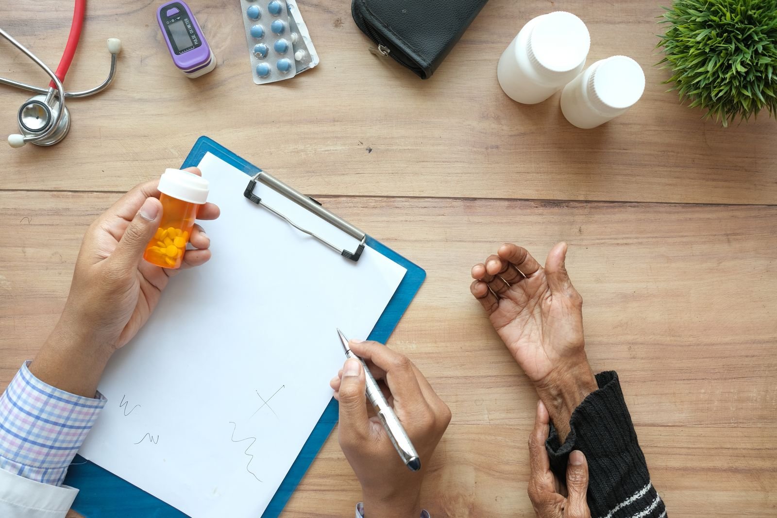 Hand holding a pill bottle over a clipboard during an appointment