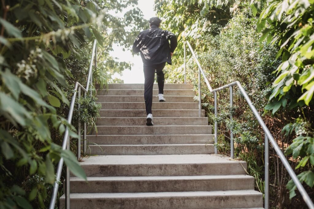 Man running up outdoor stone steps lined with greenery