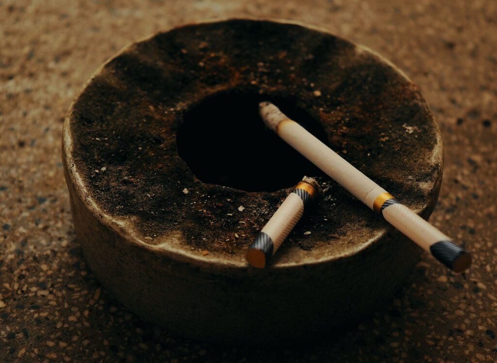 Old ashtray with burnt-out cigarettes on a rough surface
