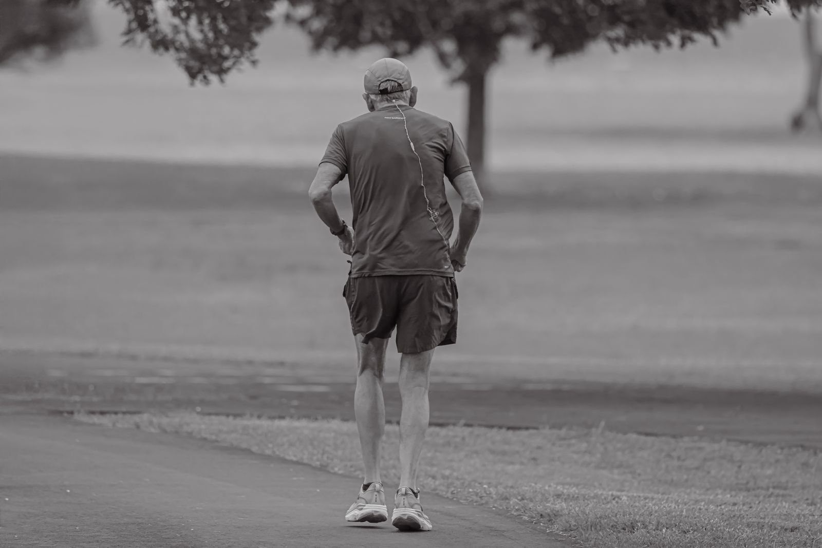 Older man jogging along a park path, seen from behind
