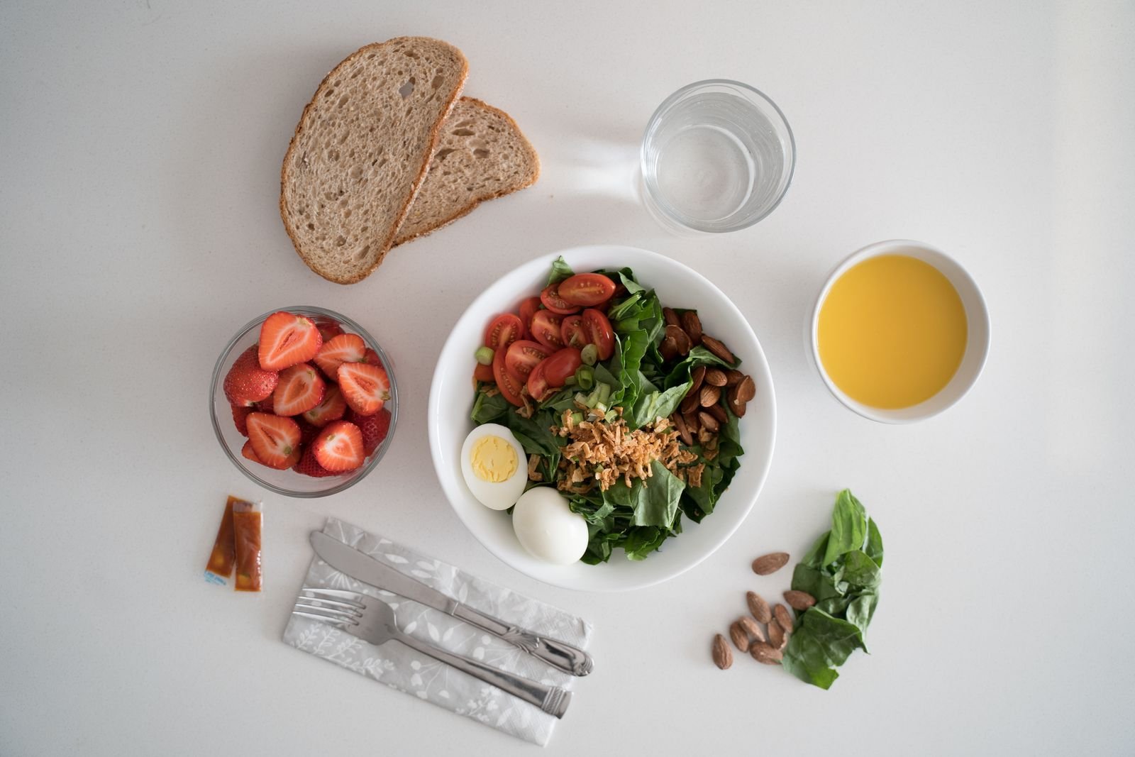Salad with egg, strawberries and wholegrain bread on a table